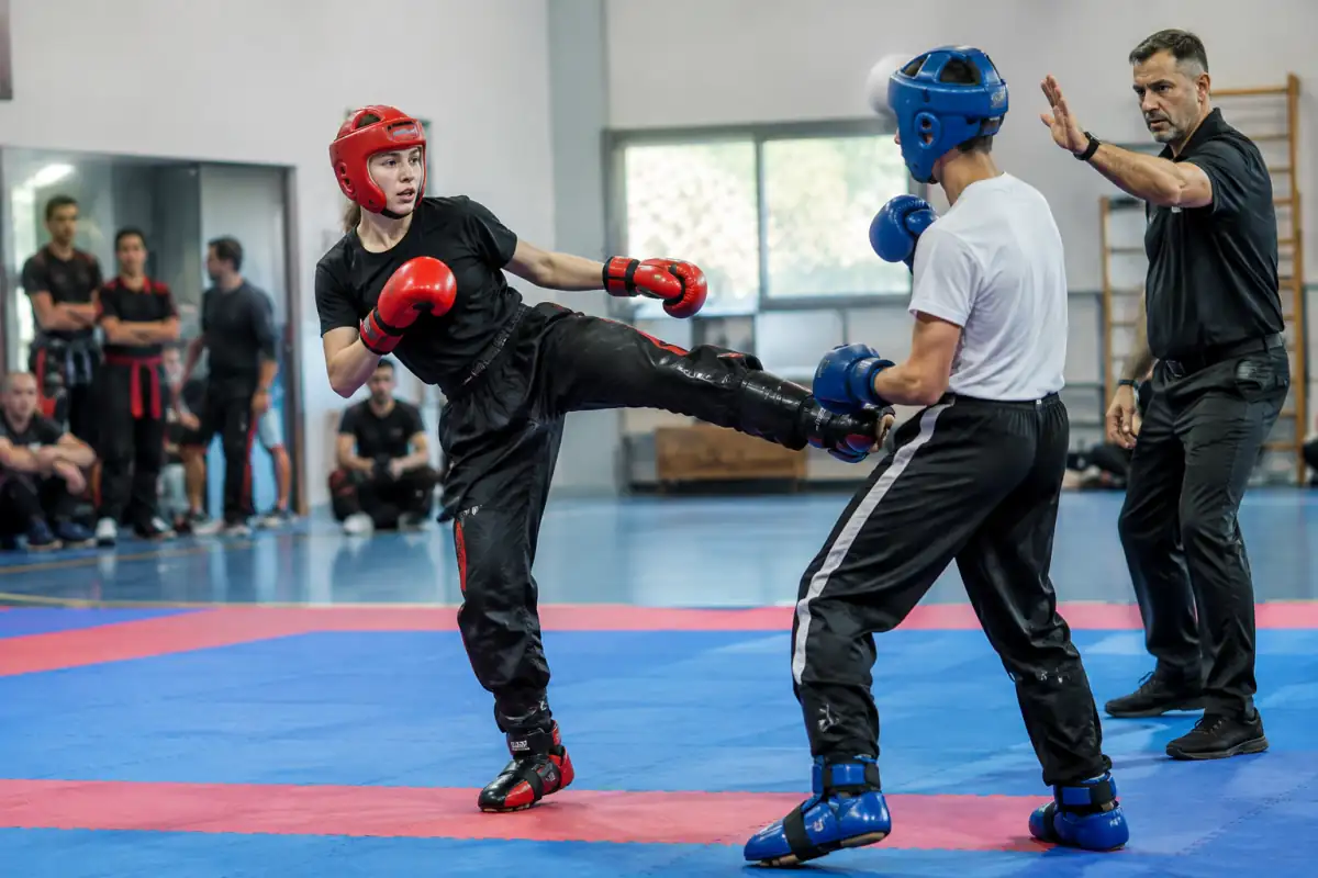 Deux pratiquants équipés échangent une touche contrôlée en point fighting sur un tatami, sous le regard de l’arbitre.