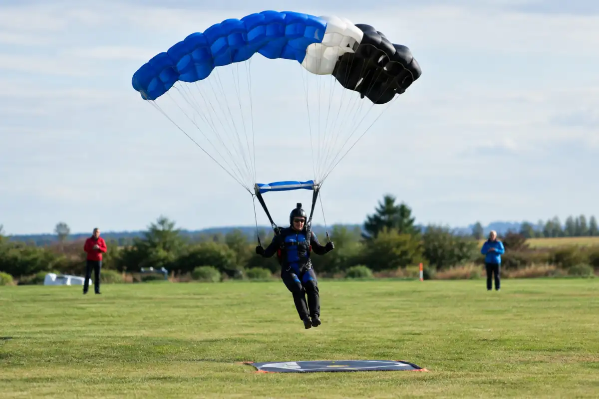 Parachutiste en approche finale sous voile pour toucher la cible de précision d’atterrissage sur un terrain dégagé.