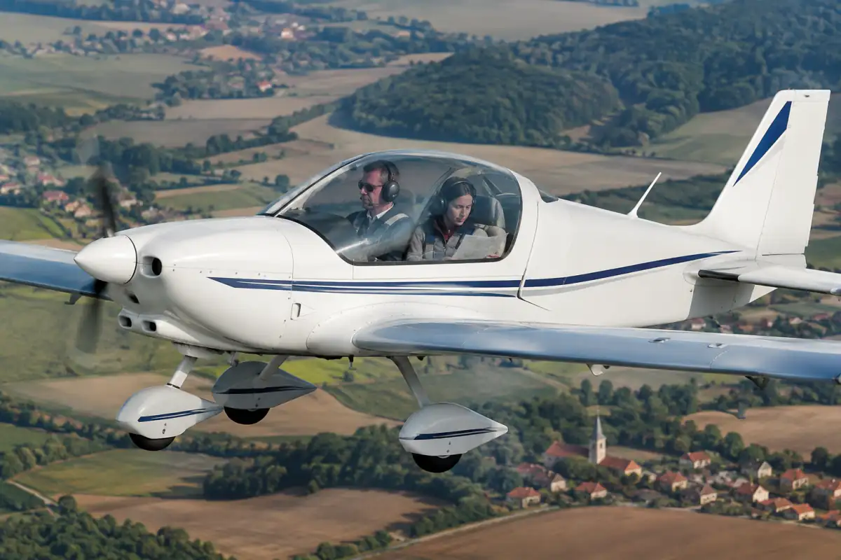 Un avion léger survole la campagne française lors d’une épreuve de rallye aérien, avec pilote et navigateur à bord.