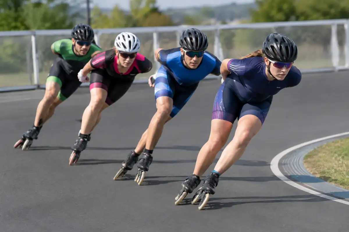 Patineurs de roller vitesse en peloton, en position basse, négociant un virage sur une piste ovale.