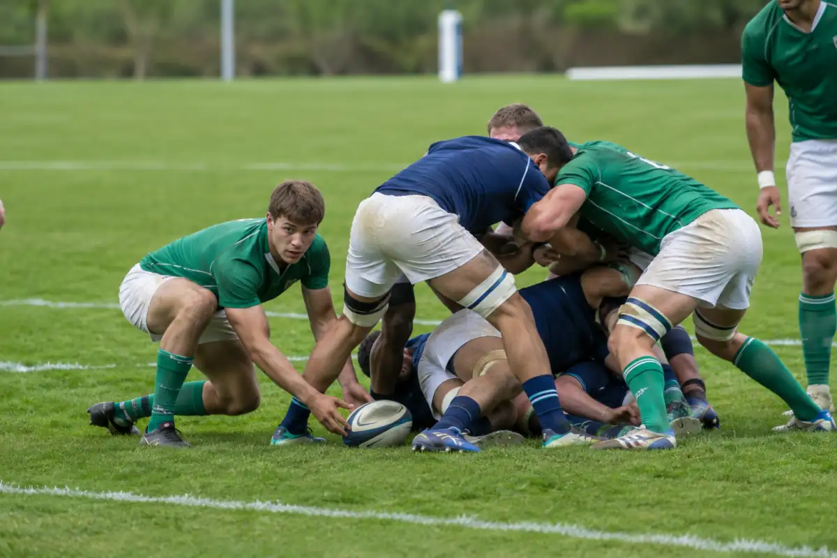 Un ruck se forme après un plaquage : les joueurs restent debout au-dessus du ballon pendant que le demi de mêlée se prépare à le jouer.