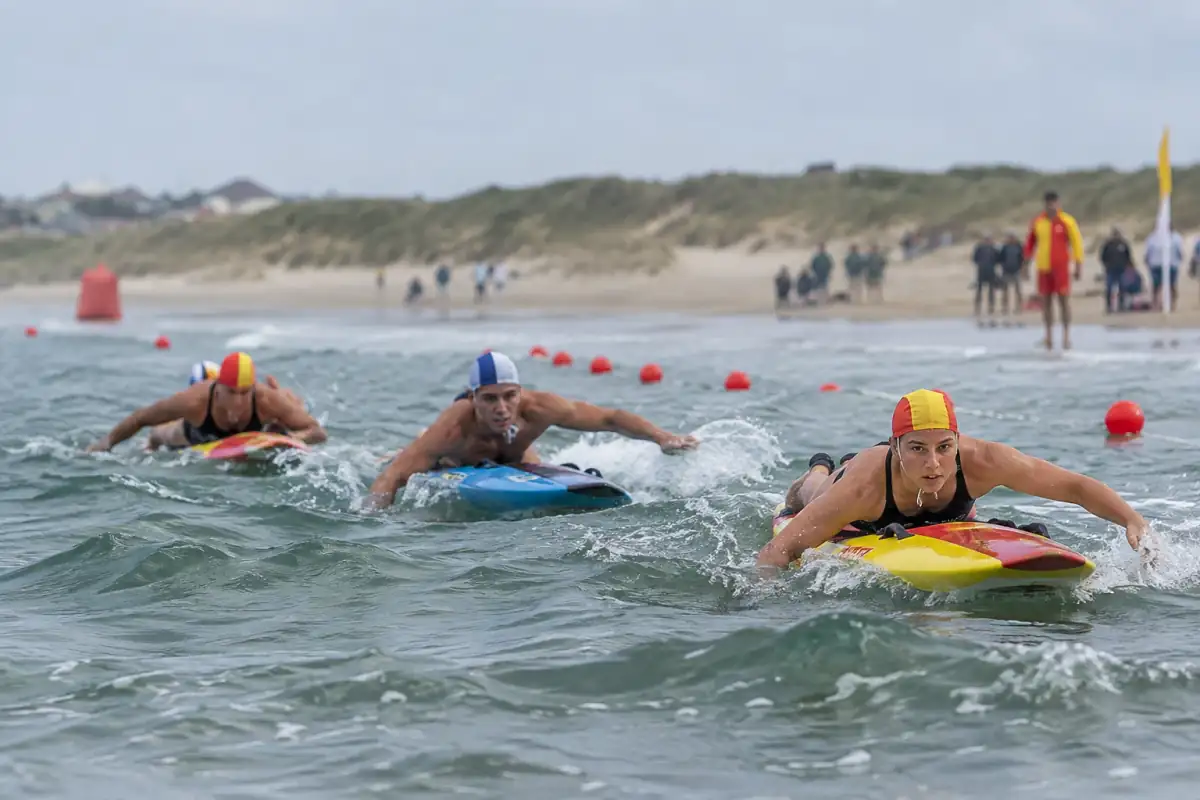 Épreuve de sauvetage sportif côtier : des athlètes pagaient sur leurs planches de sauvetage dans les vagues.