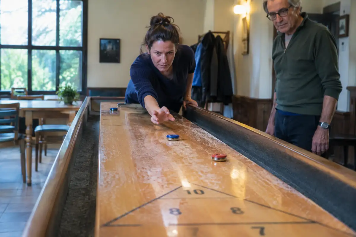 Un joueur fait glisser un palet rouge sur une table de shuffleboard de table vers les zones de score triangulaires.