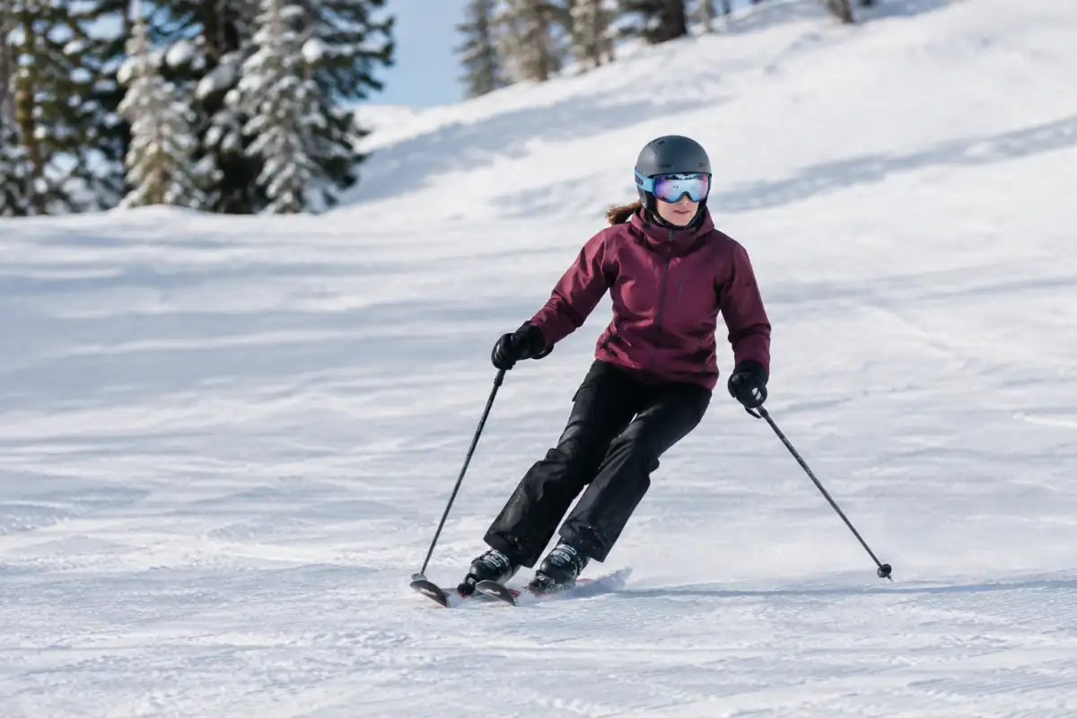 Skieur en virage parallèle sur une piste facile, jambes fléchies, skis sur les carres et regard porté vers la trajectoire.