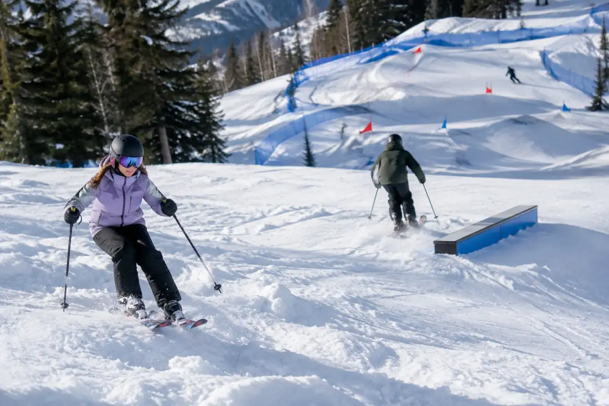 Trois skieurs découvrent les bosses, un module de snowpark et un parcours de ski cross dans une station enneigée.