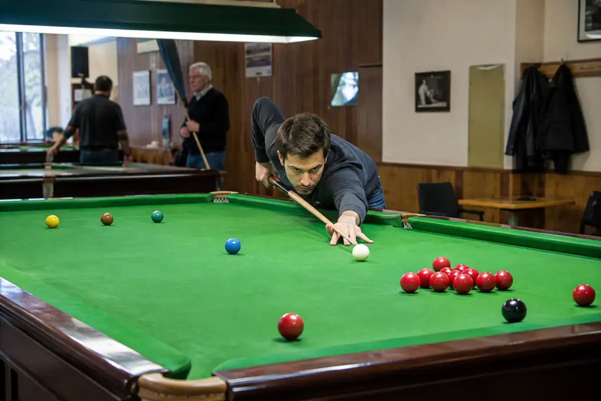 Joueur alignant sa queue sur la blanche devant des billes rouges et de couleur sur une table de snooker verte en club.