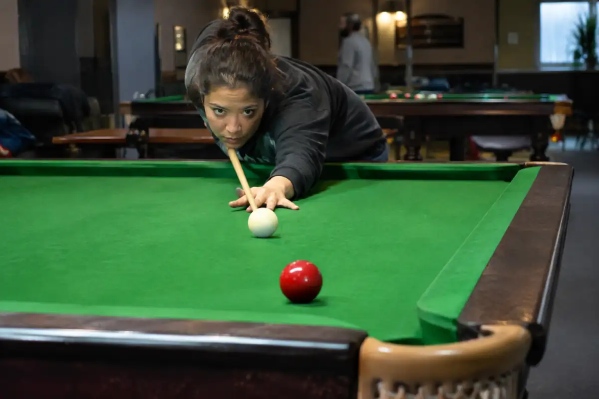 Débutant au snooker en position d’alignement pour travailler un coup droit sur une table de taille réglementaire.