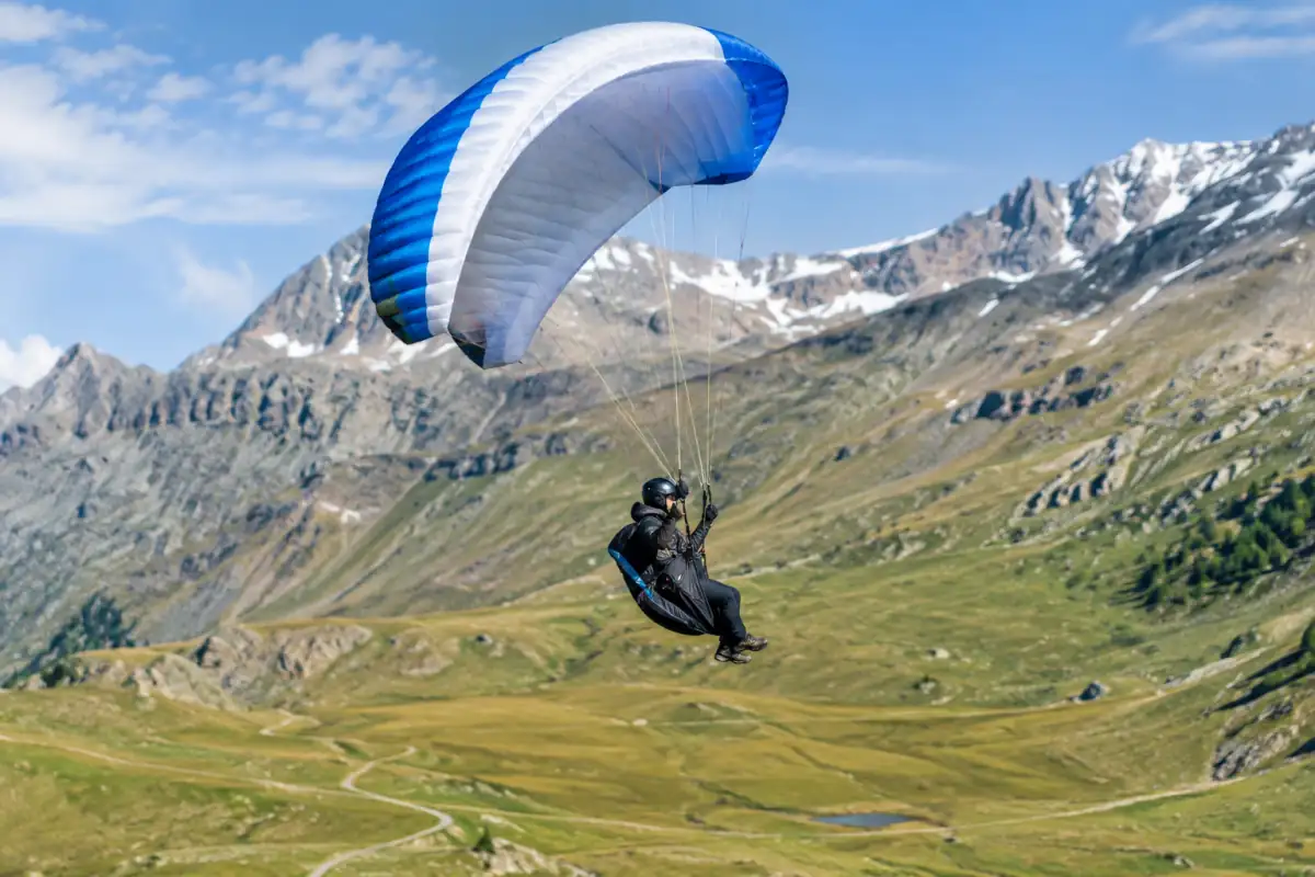 Un pilote de speed flying vole sous une petite aile au-dessus d’une pente dégagée dans les Alpes françaises.
