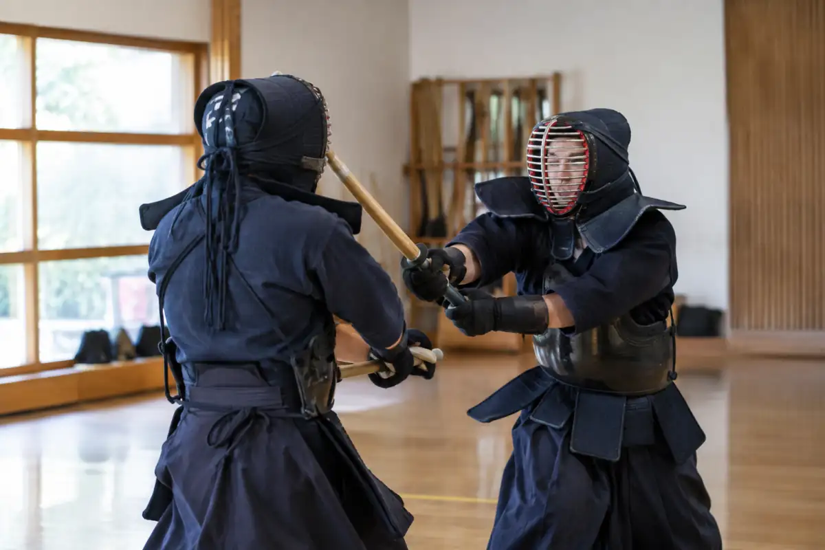 Deux pratiquants en armure échangent une attaque de tankendo avec un sabre court en bambou dans une salle d’arts martiaux.