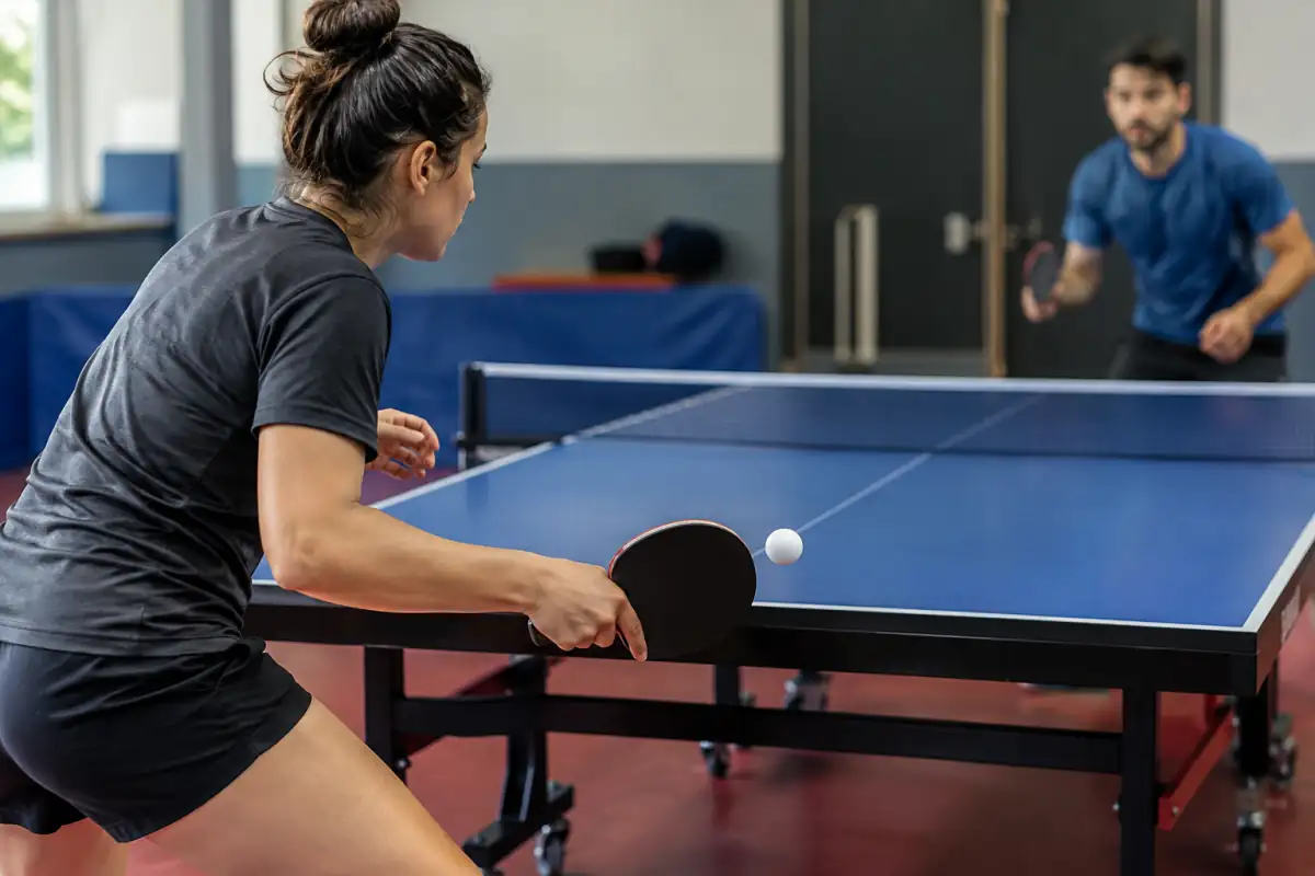 Joueur de tennis de table en position équilibrée, raquette devant le corps au contact de la balle pour travailler le revers.