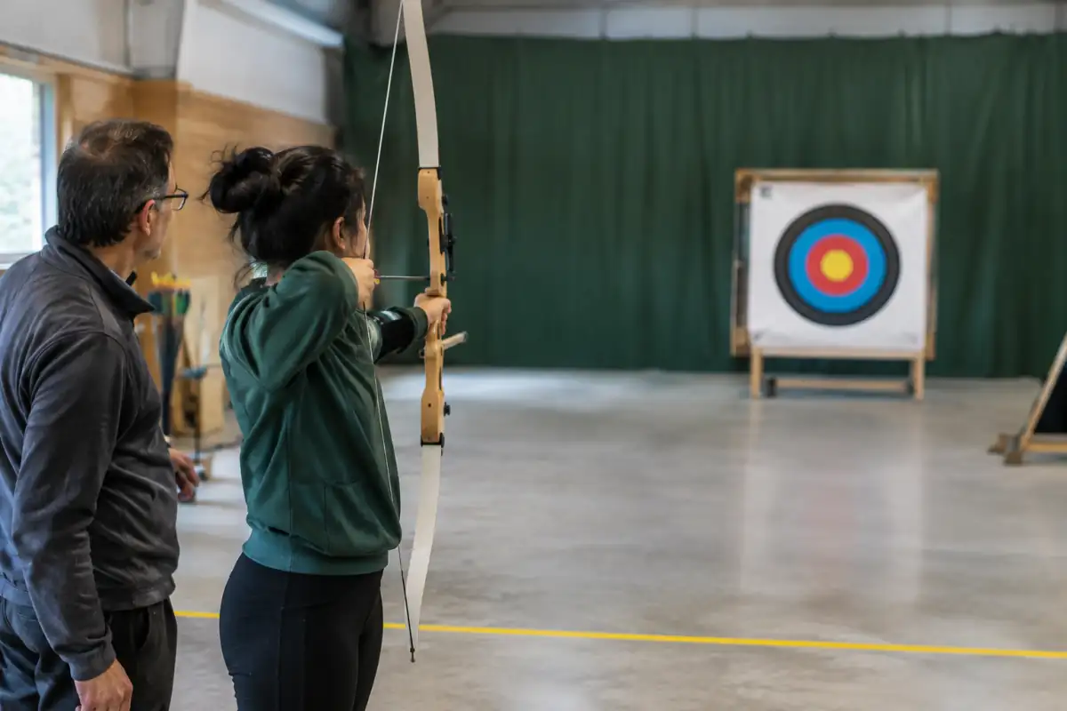 Archer débutant travaillant sa posture et son ancrage à courte distance sous l’observation d’un entraîneur.