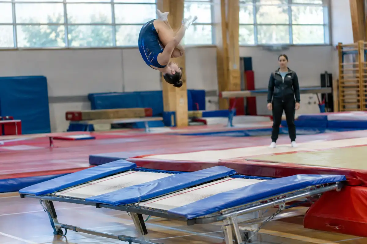 Une gymnaste réalise une figure sur un double mini-trampoline avant de se réceptionner sur le tapis dans une salle de gymnastique.
