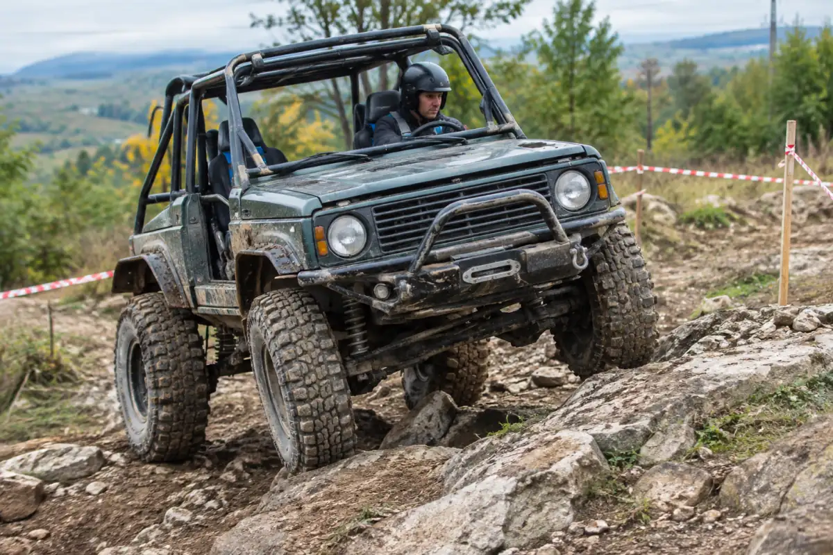 Un pilote franchit lentement une montée rocheuse au volant d’un 4x4 préparé pour le trial, sur un terrain balisé.