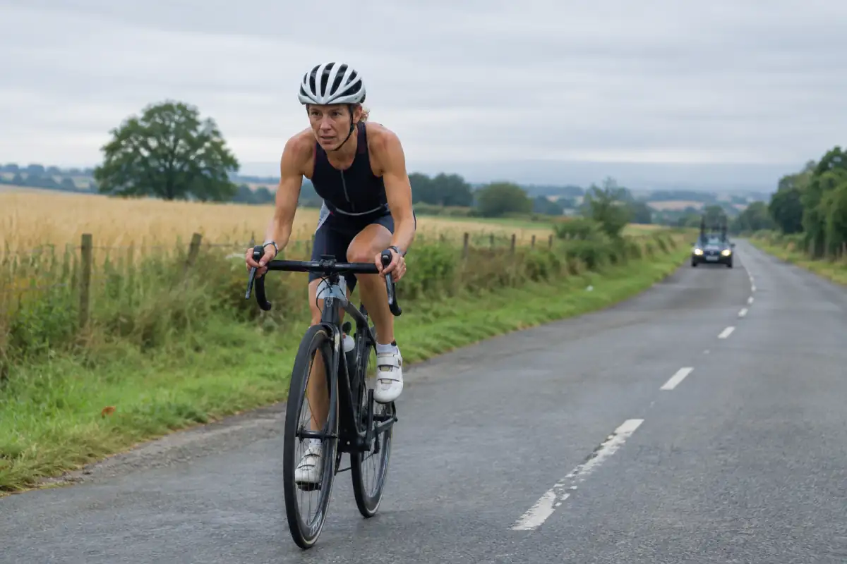 Un athlète en vélo de route sur une course d’ultratriathlon, équipé d’un casque et concentré sur une longue étape.