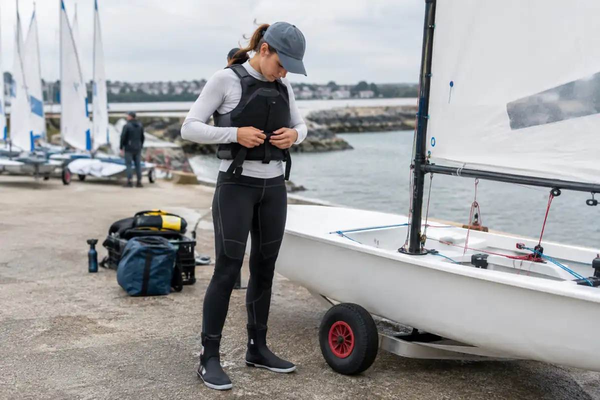 Débutant en voile vérifiant l’ajustement de son gilet et de ses chaussures avant une sortie en dériveur.