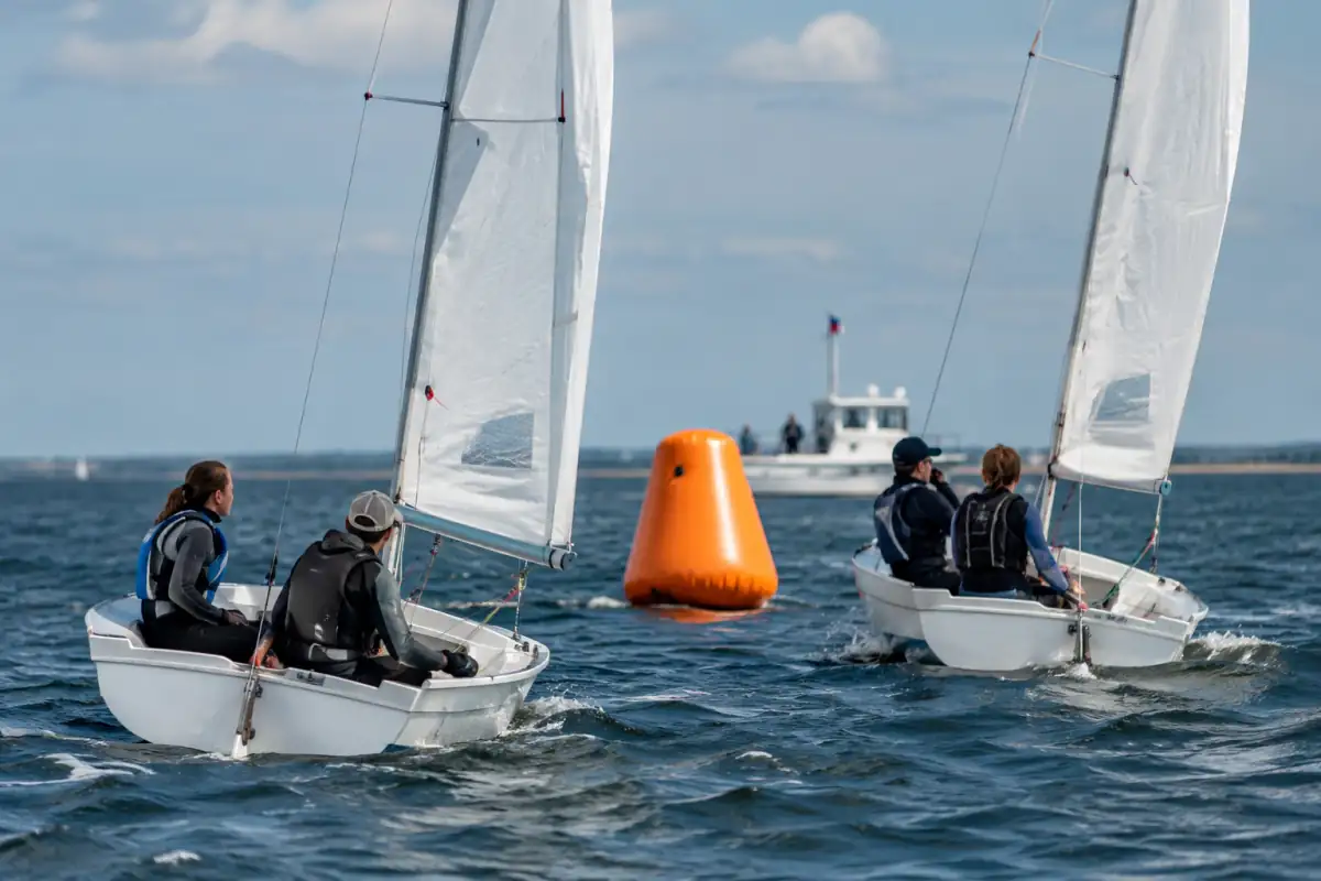 Deux dériveurs se croisent avec prudence autour d’une bouée de parcours pendant une régate à la voile.
